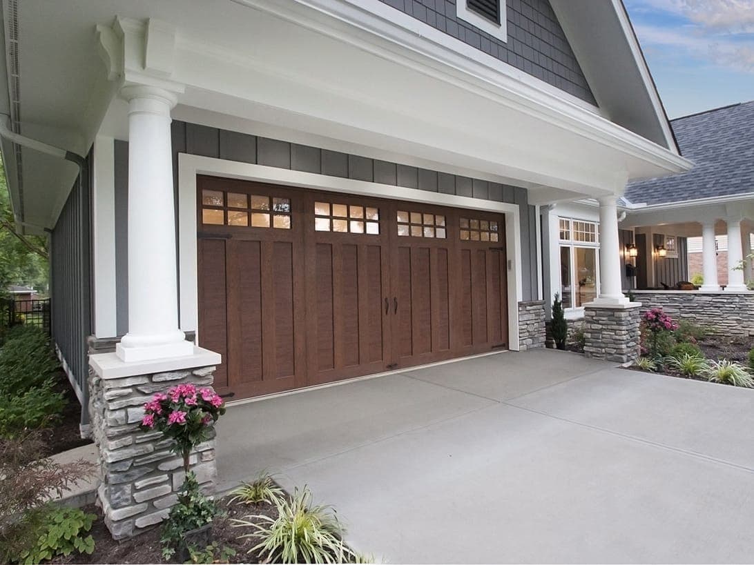 A home with a dark wood-look carriage-house garage door with windows