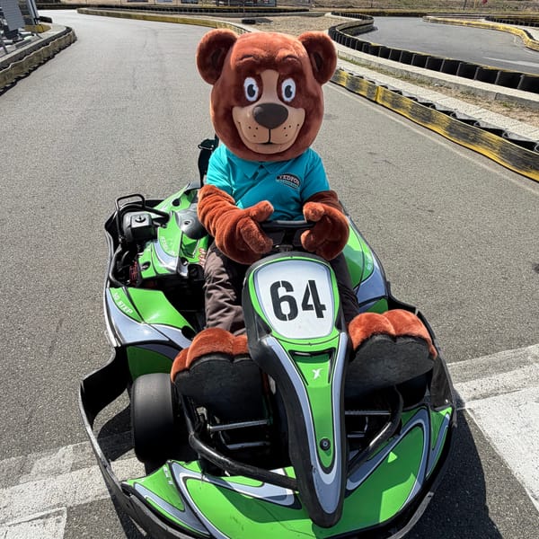 The Tedford bear mascot driving a go-kart on a local track