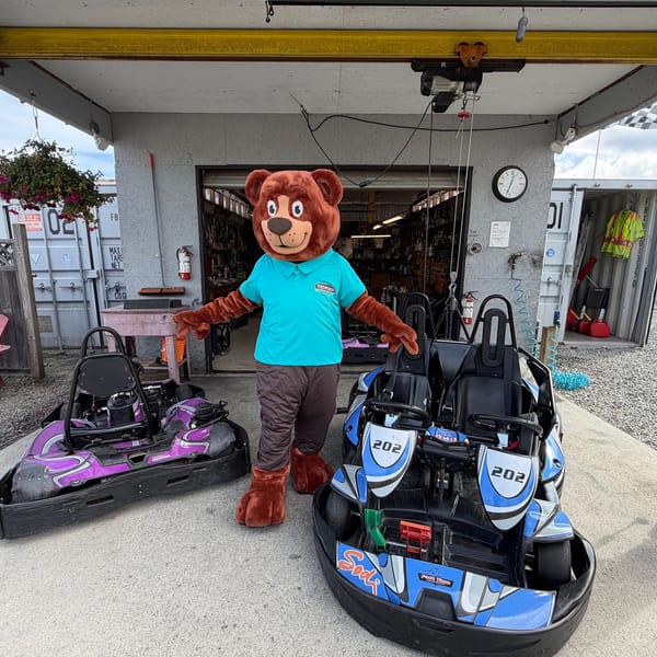 The Tedford bear mascot with go-karts at a local kart track
