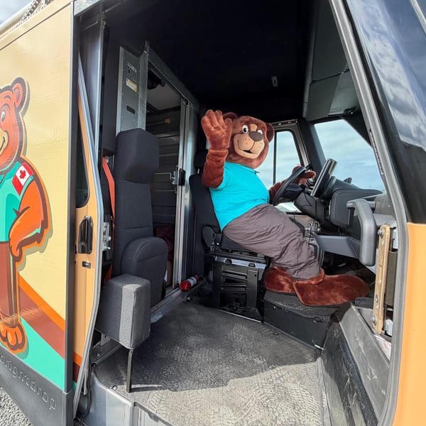 The Tedford bear mascot waving from the driver's seat of a Tedford service van