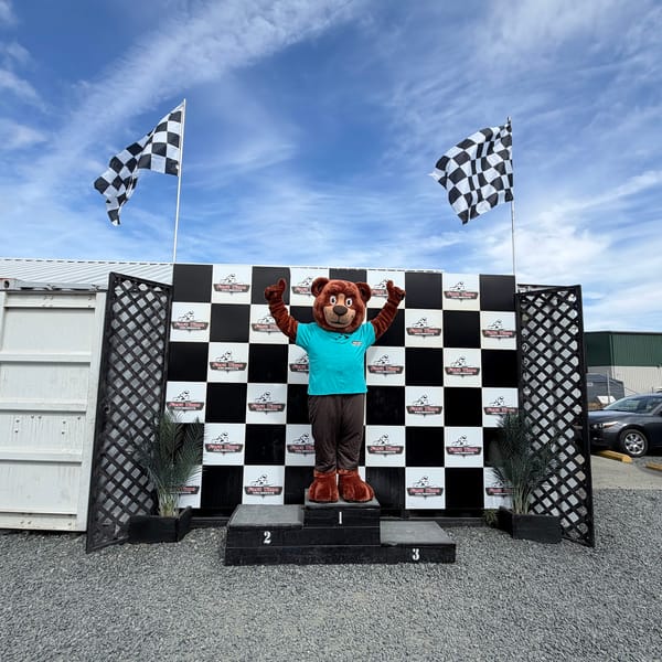 The Tedford bear mascot celebrating on a go-kart winners' podium