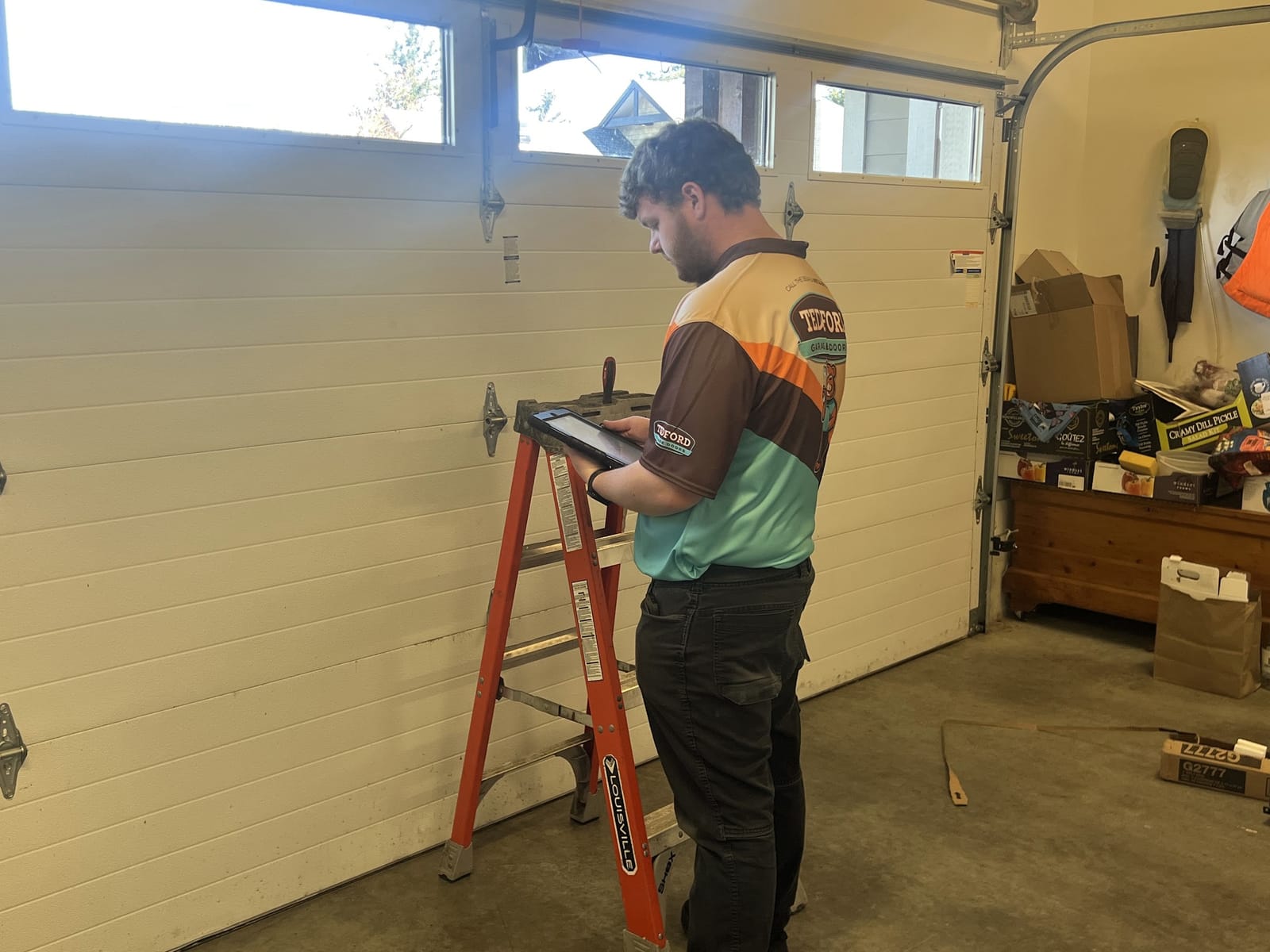 Tedford Garage Doors technician recording garage door inspection notes on a tablet