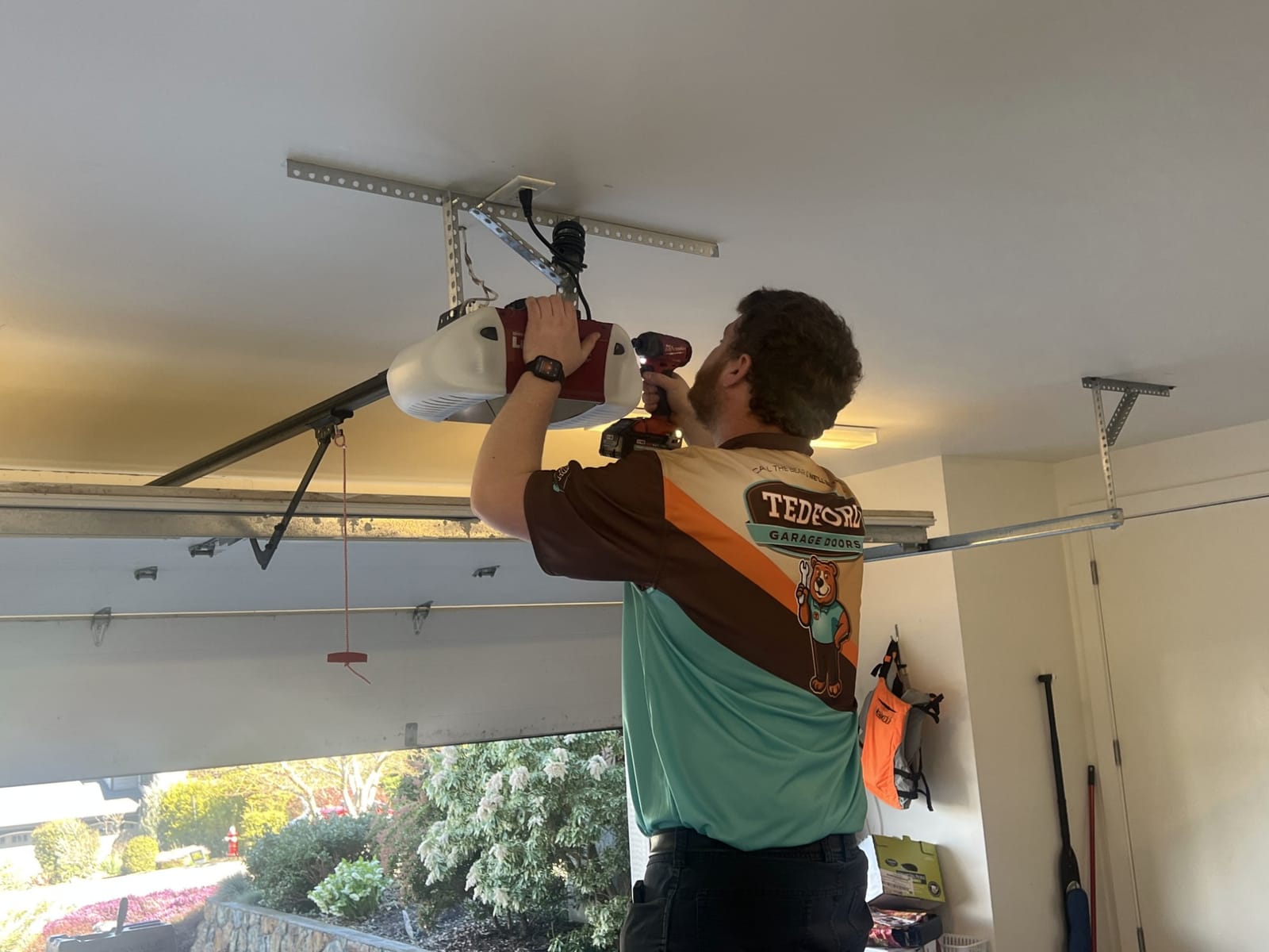 Tedford Garage Doors technician fastening a garage door opener to its ceiling bracket